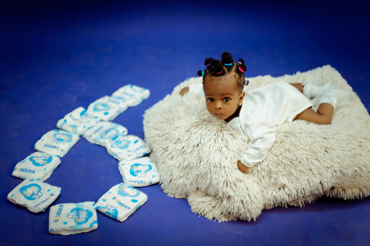 our-mission-01 Cute baby lying on a soft rug with diapers arranged in a heart shape.